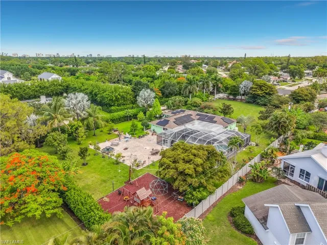 Expansive property featuring a screened-in pool, extensive patio space, mature landscaping, solar panels, and a red-mulched play area