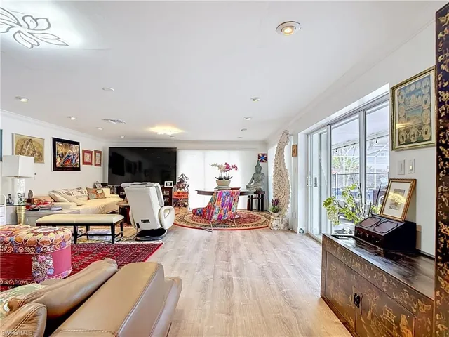 Spacious living area featuring light wood-finish flooring, recessed lighting, crown molding, and white walls