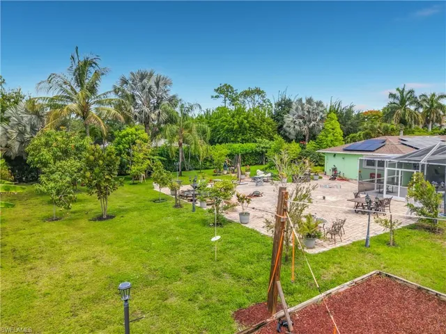 Expansive outdoor living area featuring a large paver patio, a screened enclosure, and solar panels on the roof