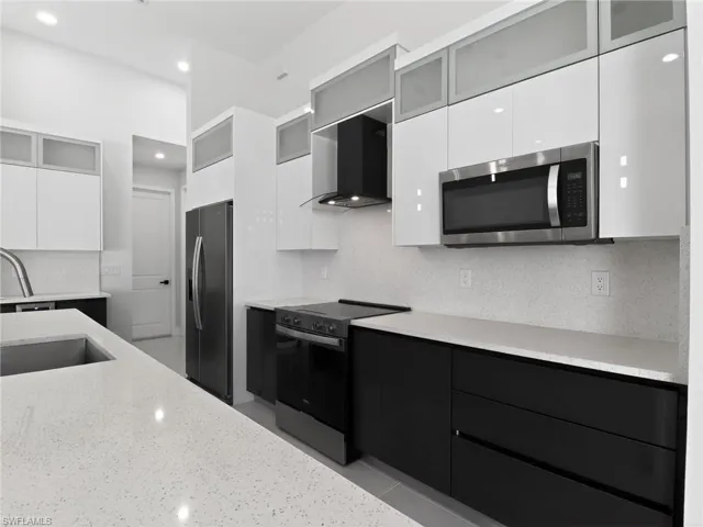 Kitchen with glass fronted cabinets, modern cabinets, stainless steel appliances, tasteful backsplash, and dual tone cabinets