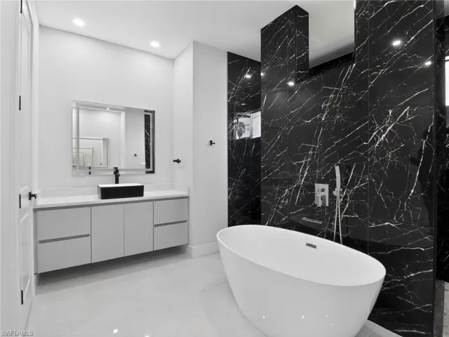 Full bathroom featuring vanity, tile walls, light marble finish flooring, a marble finish shower, and a soaking tub