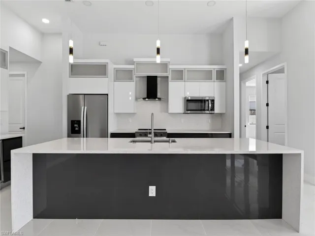 Kitchen featuring glass fronted cabinets, stainless steel appliances, light stone counters, a spacious island, and two tone cabinets