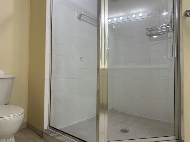 Bathroom with toilet, tile patterned floors, and a shower with shower door