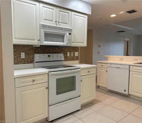 Kitchen featuring white appliances, backsplash, and light tile patterned flooring