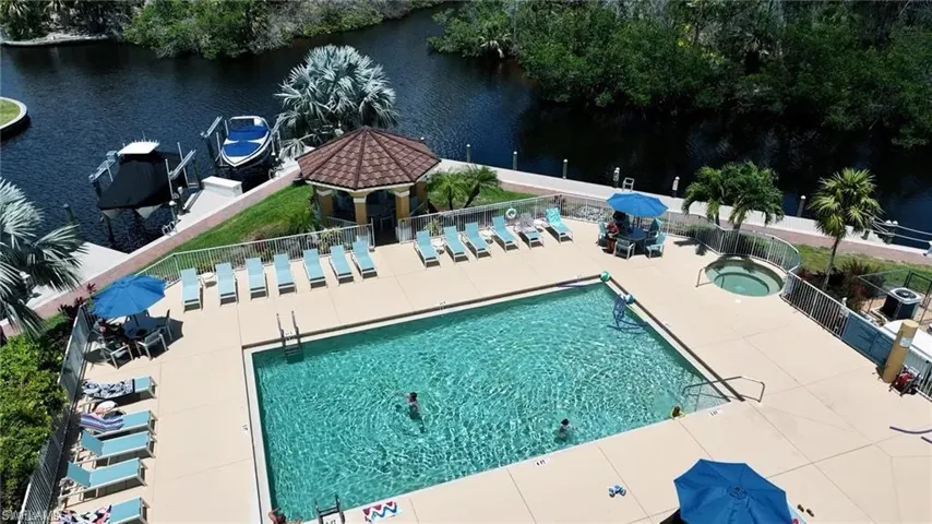 View of swimming pool with a hot tub, a water view, and a patio