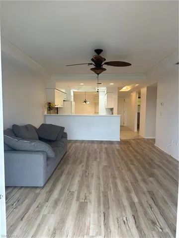 Unfurnished living room with ornamental molding, ceiling fan with notable chandelier, and light hardwood / wood-style flooring