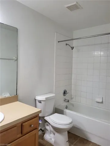 Bathroom featuring vanity, shower / washtub combination, and dark tile patterned flooring
