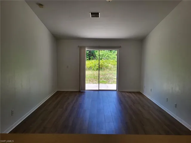Empty room featuring dark wood-type flooring and baseboards