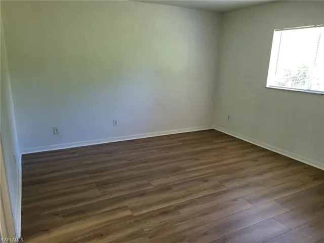 Unfurnished room with dark wood-style floors and baseboards