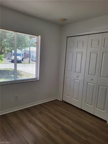Unfurnished bedroom featuring dark wood-type flooring and a closet