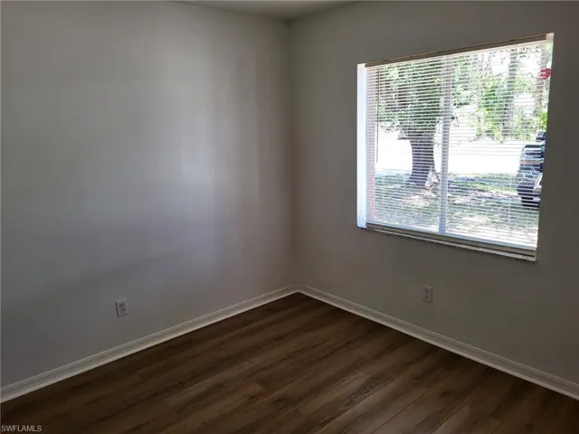 Spare room featuring dark wood finished floors and baseboards