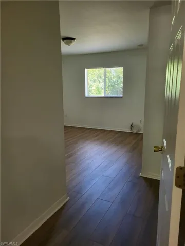 Unfurnished room with dark wood-style floors and baseboards