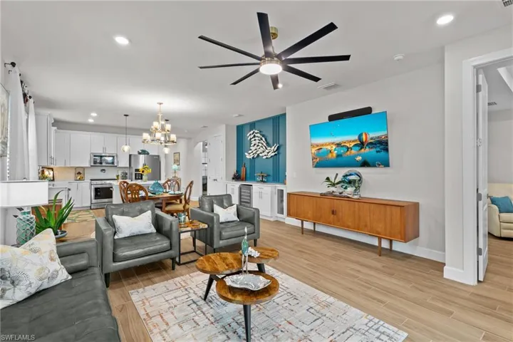 Living area featuring recessed lighting, light wood-style flooring, a ceiling fan, a chandelier, and beverage cooler