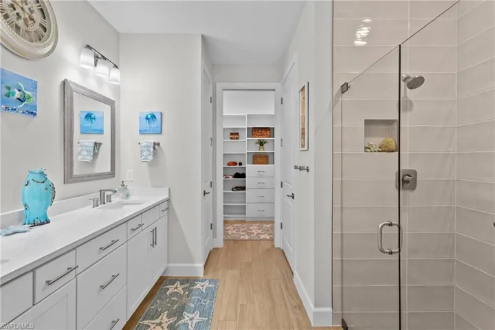 Bathroom featuring a shower stall, a walk in closet, vanity, and light wood-type flooring