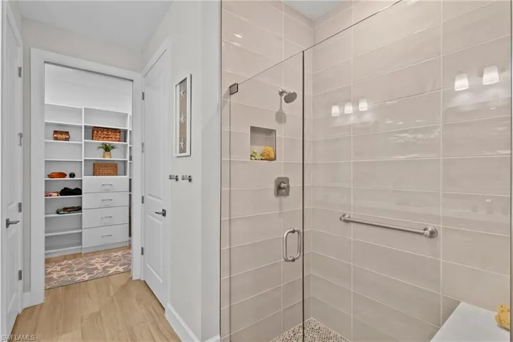Full bath featuring a stall shower, a walk in closet, and light wood-type flooring