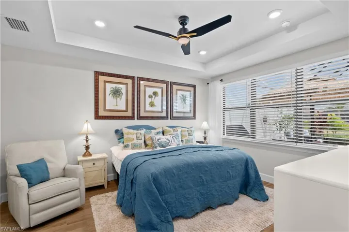 Bedroom featuring a raised ceiling, wood finished floors, a ceiling fan, and recessed lighting