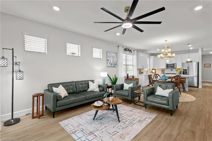 Living room with recessed lighting, a chandelier, a ceiling fan, and light wood-type flooring