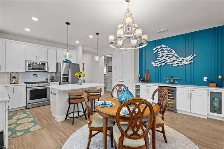 Dining area featuring beverage cooler, light wood-type flooring, recessed lighting, and a chandelier