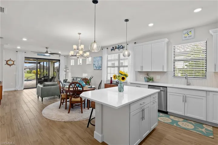 Kitchen featuring open floor plan, light wood-type flooring, a breakfast bar area, white cabinets, and a kitchen island