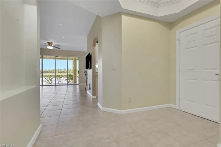 Foyer with arched walkways, ceiling fan, and light tile patterned floors