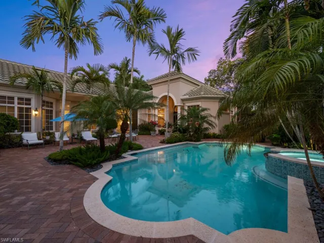 Pool at dusk featuring a patio and an in ground hot tub