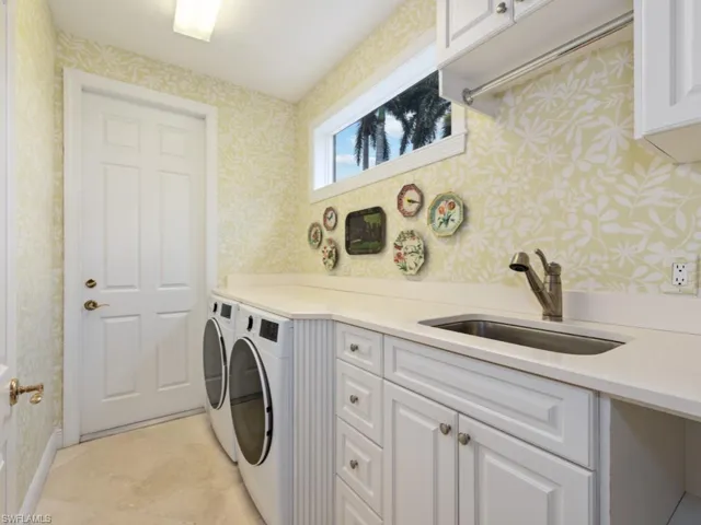 Laundry room featuring sink, washer and dryer, cabinets