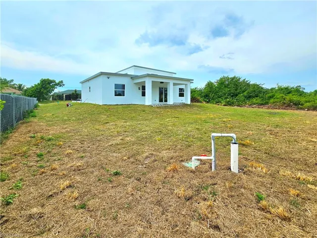 View of front of home featuring a front lawn, stucco siding, and fence
