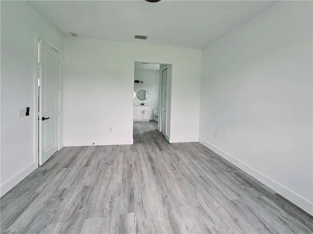 Unfurnished bedroom featuring baseboards, visible vents, and wood finished floors