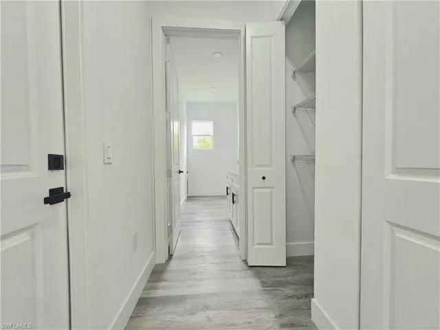 Hallway with baseboards and wood finished floors