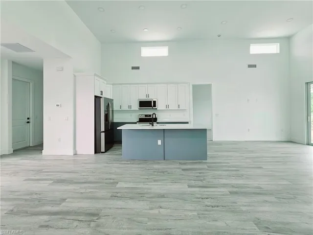 Kitchen featuring a high ceiling, open floor plan, a sink, and appliances with stainless steel finishes