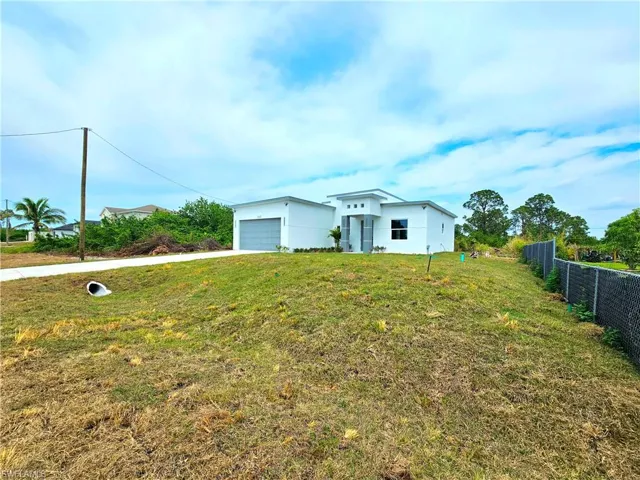 View of front of house featuring a front yard, stucco siding, and fence