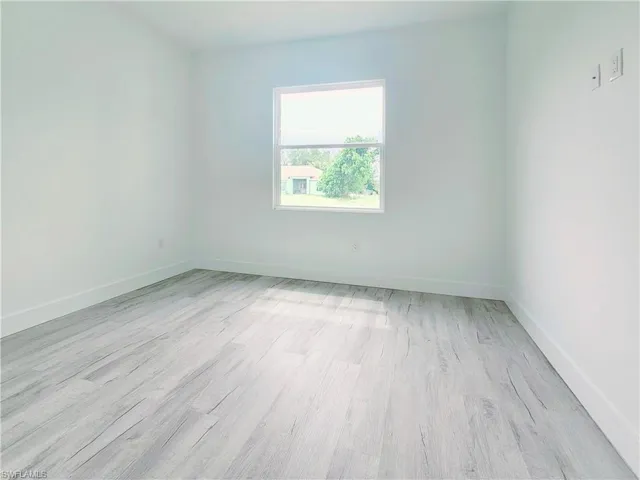 Empty room with baseboards and light wood-style flooring