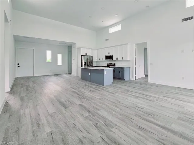 Kitchen featuring light countertops, visible vents, stainless steel appliances, white cabinetry, and open floor plan
