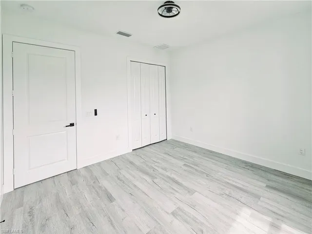 Unfurnished bedroom with baseboards, visible vents, a closet, and wood finished floors