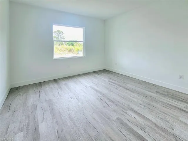 Spare room with baseboards and wood finished floors