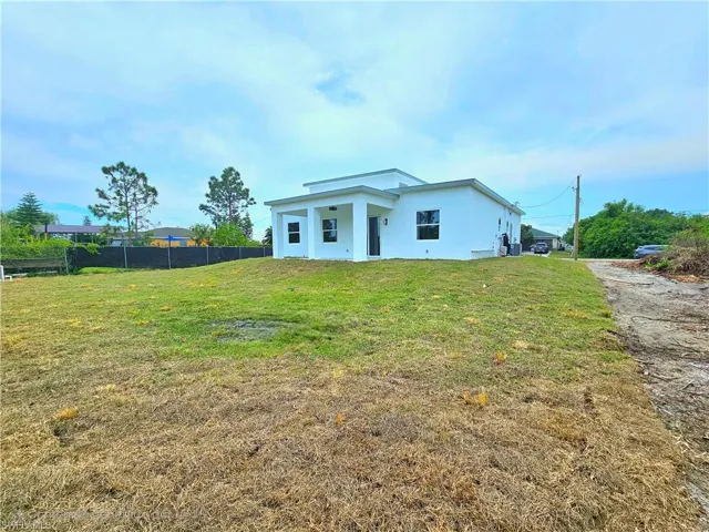 View of front of house featuring a front yard, stucco siding, and fence