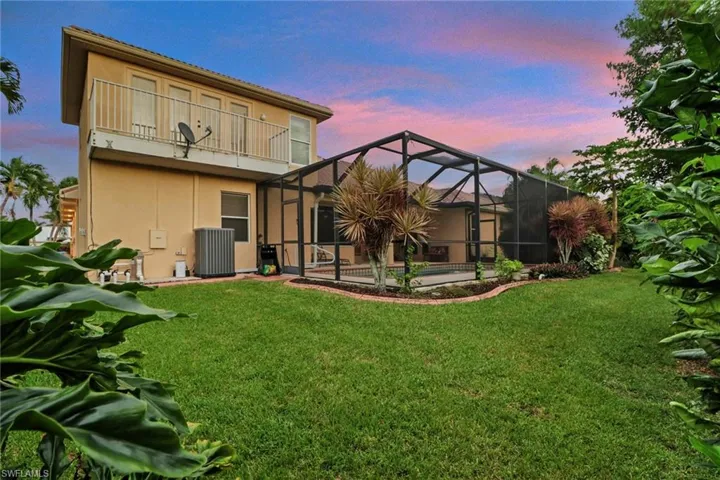 Rear view of property featuring a sunroom, glass enclosure, a pool, and stucco siding