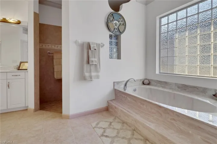 Full bathroom featuring vanity, a bath, a walk in shower, and light tile patterned flooring