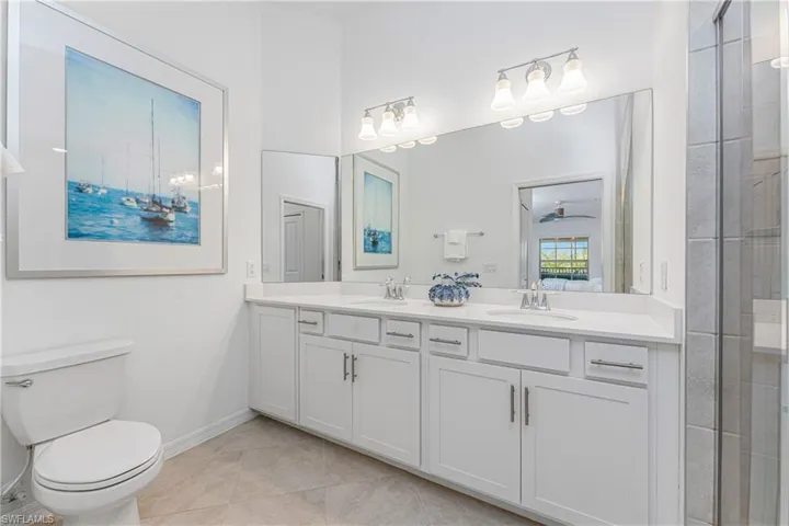 Bathroom featuring double vanity, light tile patterned floors, and tiled shower