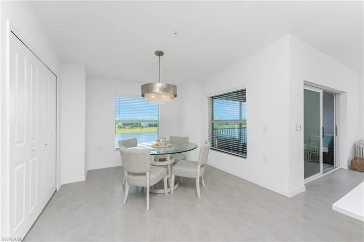 Dining area with light tile patterned floors, plenty of natural light, a chandelier, and a water view
