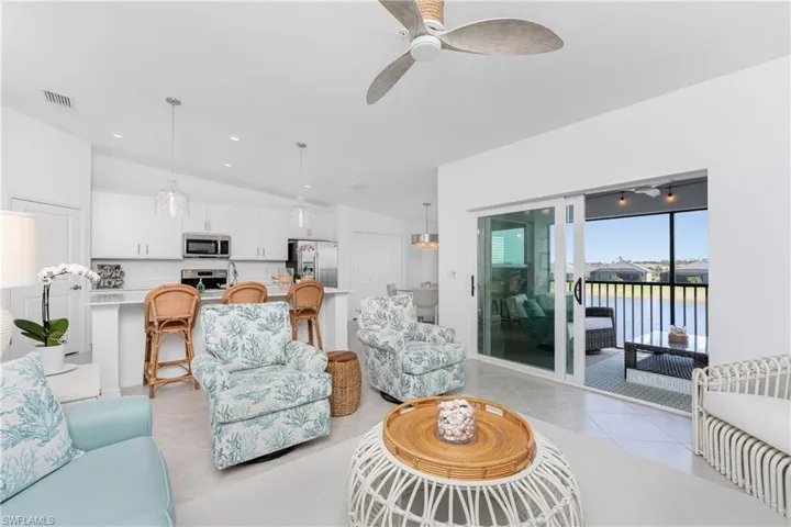 Living room featuring light tile patterned floors, vaulted ceiling, ceiling fan, recessed lighting, and a water view