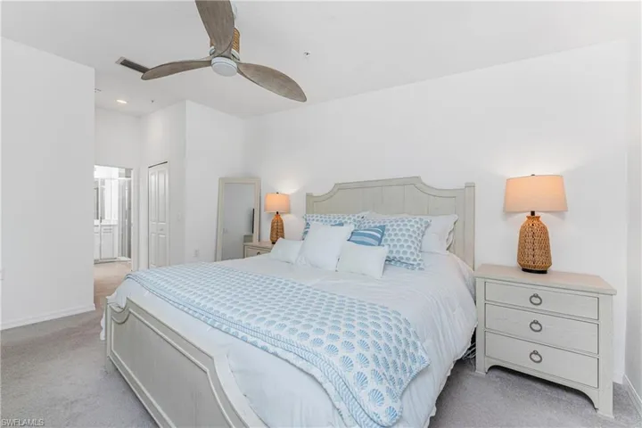 Bedroom featuring light carpet, a ceiling fan, a closet, and ensuite bathroom