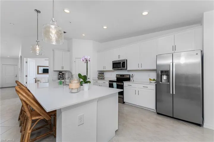 Kitchen with stainless steel appliances, white cabinetry, a kitchen breakfast bar, recessed lighting, and a center island with sink