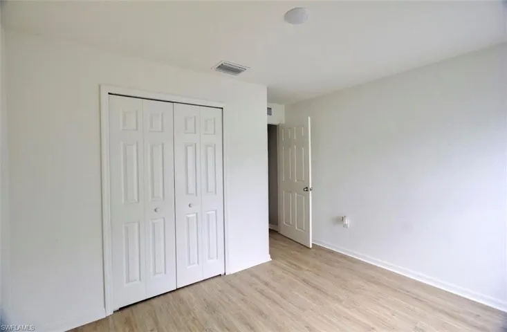 Unfurnished bedroom featuring light wood-style flooring, baseboards, a closet, and visible vents