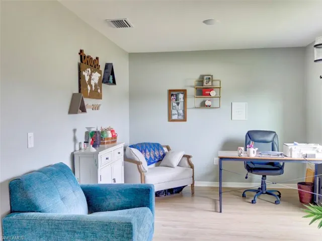 Office space with light wood-style flooring, baseboards, and visible vents