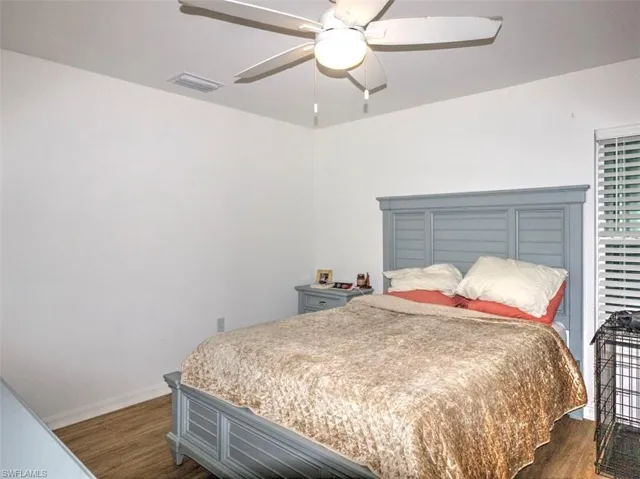 Bedroom with a ceiling fan, dark wood finished floors, baseboards, and visible vents