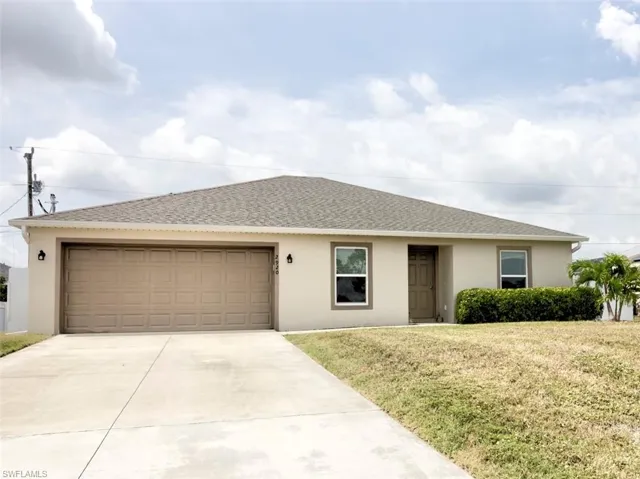 Ranch-style house featuring a front yard, stucco siding, an attached garage, and concrete driveway