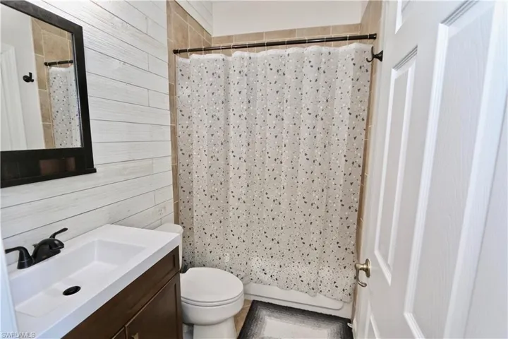 Bathroom featuring a wood-finish vanity with an integrated white sink, matte black faucet, and a framed mirror