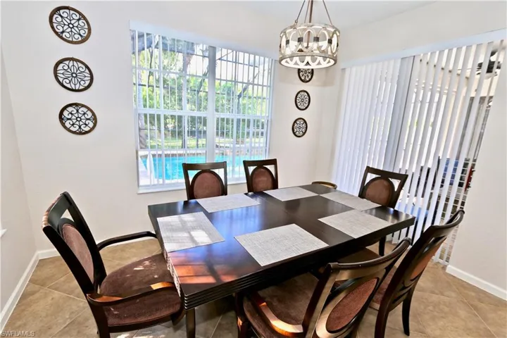 Dining area with tiled flooring, a modern chandelier, and ample natural light from a large window