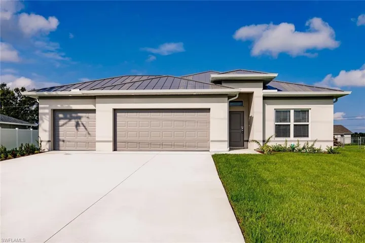 Prairie-style home featuring stucco siding, a garage, driveway, and a standing seam roof